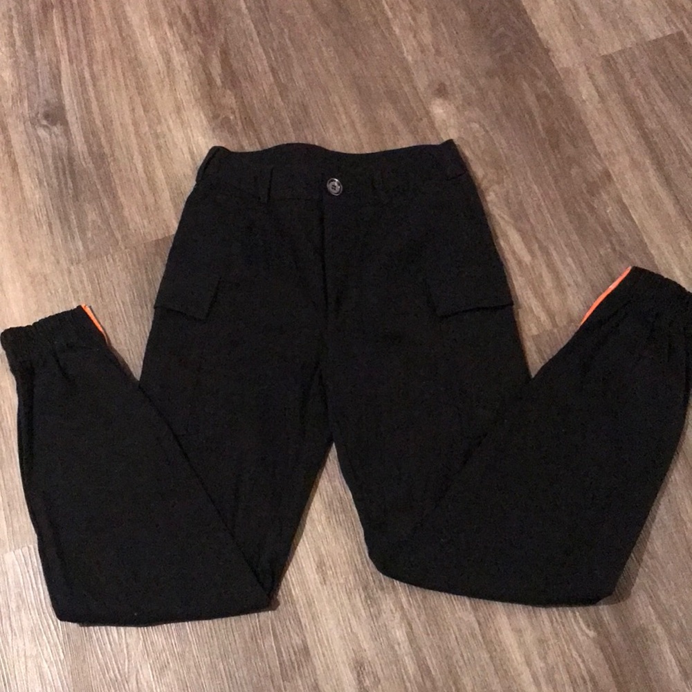 Black small cargo pants with a pocket on each leg. Has a zipper on ankle.